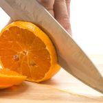 Muškarac velikim nožem seče pomorandžu